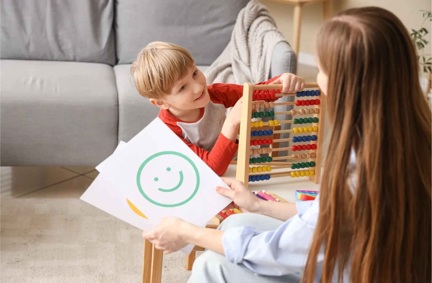Criança mostrando desenho de rosto sorridente a uma profissional durante atendimento