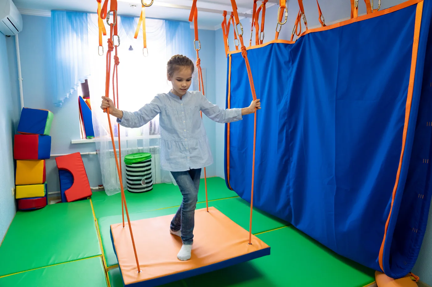 Menina se equilibrando em plataforma suspensa em sala de integração sensorial